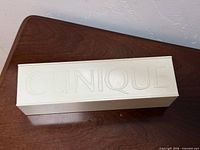 Clinique off-white plastic storage box, lid closed, logo visible