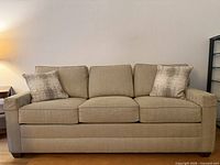 front view of beige Ethan Allen three-seat sofa with two accent pillows