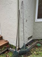 Both rakes leaning against exterior wall