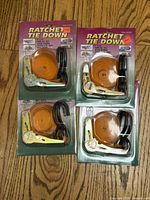 Four packaged orange ratchet tie-down straps