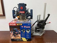 Ryobi RE175 plunge router on original box beside drill press stand