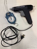 Glue gun and cat-shaped hanging scale with cords and hooks visible