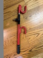 Full view of red steering wheel lock showing both hooks and telescoping bar