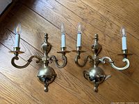 Front view of both brass wall sconces showing arms, bulbs, finish