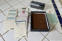 Binder in box, hole punch, refill packs displayed on tile surface