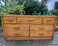 Front view showing all seven drawers, wood finish, metal pulls