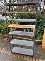 Front view of full metal shelving unit showing six wooden shelves