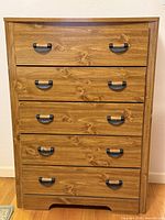 Front view of five-drawer chest, showing wood veneer finish and black handles