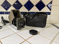 Projector front, lens cap, carry case visible