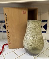 Vase standing beside wooden box showing full form and box inscription