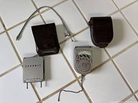 Both Sekonic meters, both leather cases, straps visible