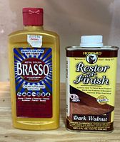 Front view of Brasso metal polish bottle and Howard Restor-A-Finish can
