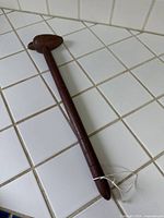 Full view of wooden massage hammer on tiled surface