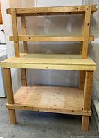 Full view of wooden workbench showing upper shelf, main work surface and lower shelf