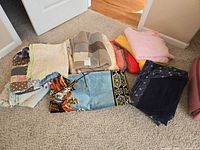 Group of throw blankets, quilts and wall carpet laid on carpeted floor