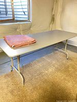Gray folding table with pink tablecloth folded on top
