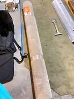 Rolled beige/tan rug on floor with packaging
