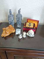 All items in lot on glass cabinet: two ceramic warriors, wooden Buddha, three small porcelain figurines, red wooden box open