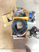 overview of box with large cable coil, boxed accessory, yellow envelope, small open box with device