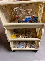 Front view of beige rolling cart showing three drawers filled with wooden craft parts