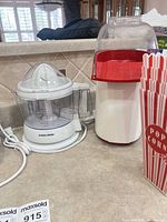 Juicer, popcorn maker, and popcorn box grouped on countertop