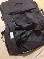 Black nylon garment bag lying open showing interior and handle