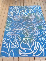 Full view of blue botanical outdoor area rug on deck