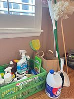 Crate with liquid cleaners, mop, broom, dustpan, fly swatter, bleach jug