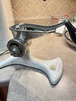 Overall side view showing cast grinder body and white freestanding base