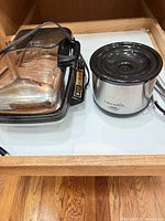 Closed waffle maker beside Crock-Pot in drawer