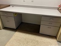 Front view of gray laminate desk showing six drawers and open knee space