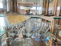 Shelf with olive motif glasses, blue stem glasses, bottle stoppers, bead garland