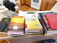 Overall view of three stacks of books on countertop showing variety of titles and bindings