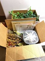 Overview of open box with berry sprays, faux flowers, plastic container, flat albums, second box of ivy