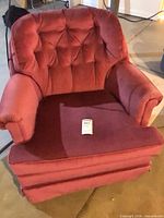 Front view of maroon velvet tufted armchair showing seat, back, and skirted base