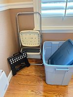 Group shot showing metal two-step stool folded, plastic step stool folded, and large blue storage tote with lid
