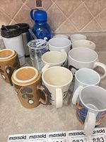 Group shot of all mugs, travel mugs, water bottle and tumbler on countertop