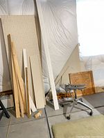 Overall view of pegboard, assorted boards, chair base, cabinet doors and sign