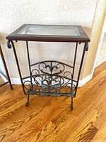 Front view of wrought iron accent table with glass top and magazine rack