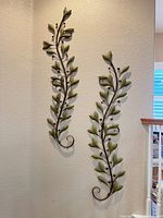 Two matching metal vine wall sculptures mounted on wall