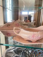 Porcelain covered dish and gravy boat displayed in cabinet