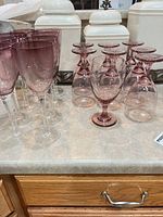 Group view of tall and short pink glasses on countertop