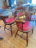Three of the four Windsor armchairs showing wood frames and red seats