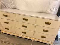 Front view of off-white nine-drawer dresser with brass recessed pulls