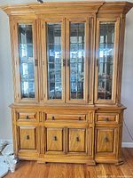 Front view of oak china cabinet with closed glass doors and lower storage