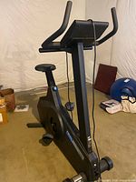 Full left-side view of black Tectrix BikeMax upright stationary bike showing console, seat, pedals and frame