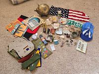 Overview of lot contents: flags, piggy bank, scout items, license plate, cap, plush bear, rocks, shells