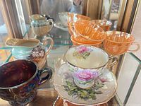 Group of assorted teacups, saucer and creamer in display cabinet