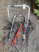 Overall view of aluminum two-bike trunk rack with attached straps and separate red hand pump