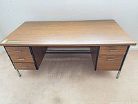 Front view of rectangular woodgrain desk showing drawer configuration and metal legs